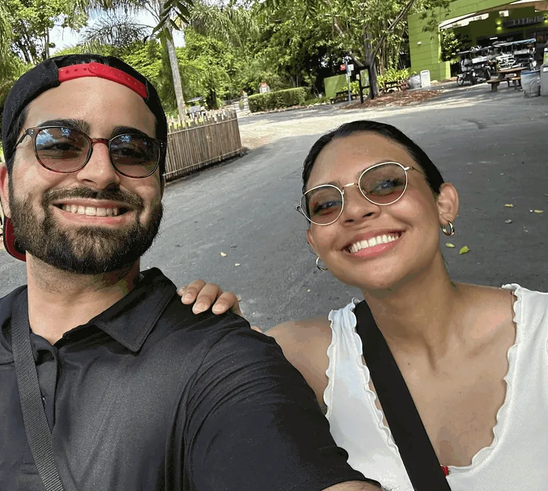 Aramis, owner of Big Mouth Junk Removal, smiling outdoors with his wife
